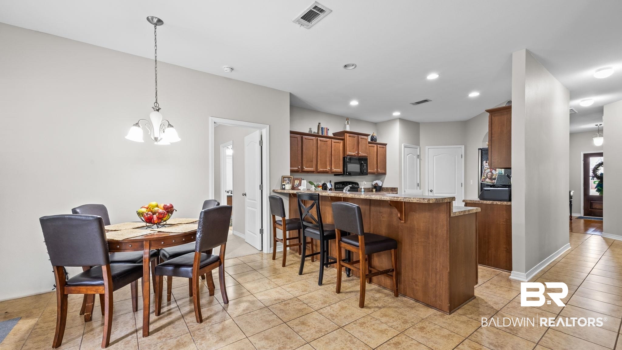 1090 Melbourne Court Foley, AL 36535 - Photo 37 of 38 Kitchen featuring a breakfast bar, a peninsula, wood finish cabinetry, a chandelier, and black microwave