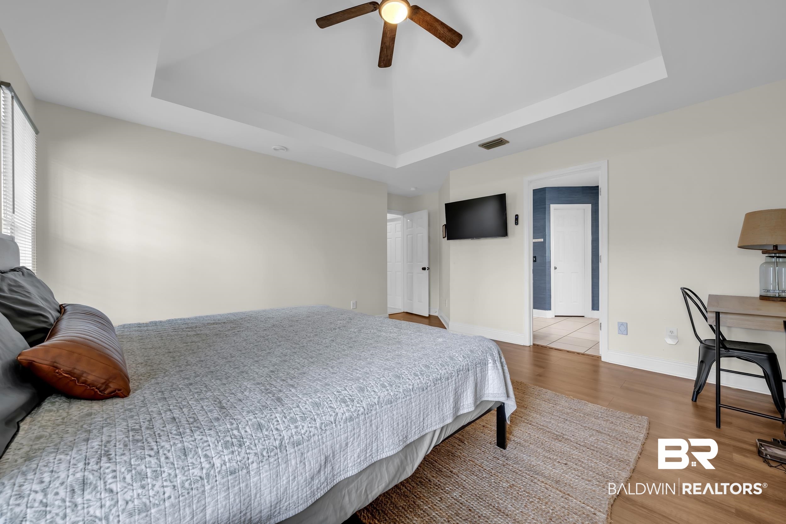 509 Loblolly Court Foley, AL 36535 - Photo 14 of 26 Spacious bedroom featuring a tray ceiling with a ceiling fan, wood-finish flooring, and light-colored walls