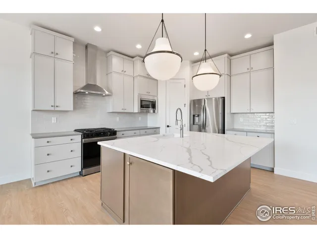 a kitchen with a sink a island a stove cabinets and a chandelier