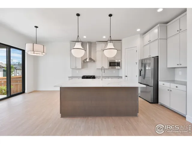 a kitchen with stainless steel appliances a refrigerator a sink and wooden floor
