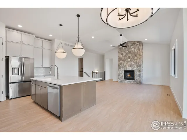 a very nice looking open kitchen with a sink a refrigerator and a fireplace