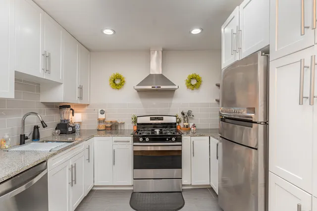 a kitchen with a refrigerator a stove and white cabinets