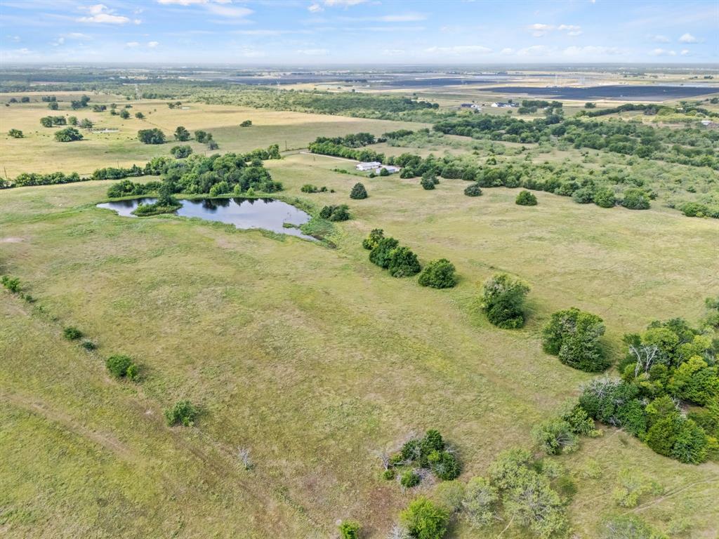 0 Fm Road Kaufman, TX 75142 - Photo 5 of 13 Expansive rural landscape featuring a natural pond surrounded by varied green foliage, open fields, and scattered trees under a partially cloudy sky