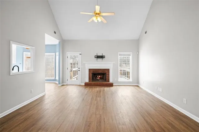 a view of an empty room with wooden floor and a fireplace