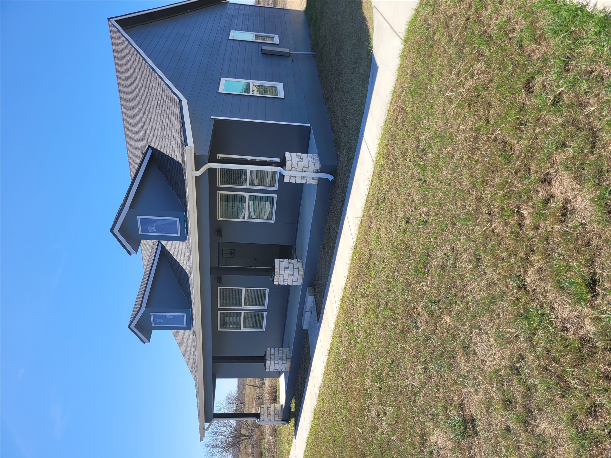 422 A Road Stockdale, TX 78160 - Photo 3 of 40 A charming blue home with dormer windows and a welcoming covered porch, perfect for enjoying outdoor living.