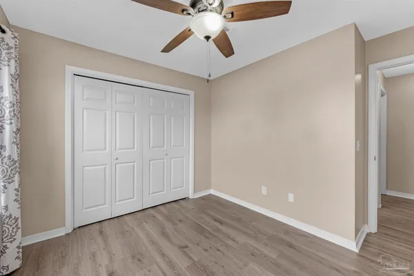 an empty room with a ceiling fan and wooden floor