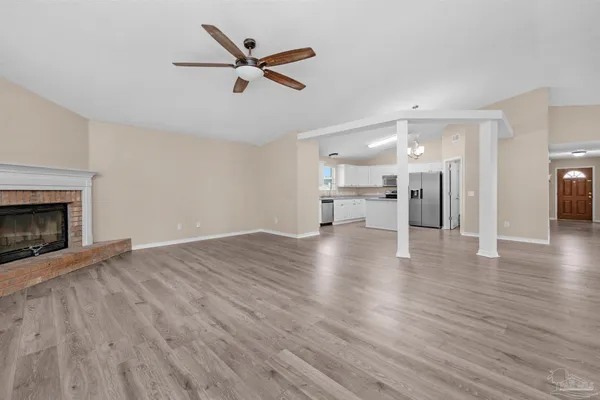 a view of a livingroom with a fireplace a ceiling fan and windows