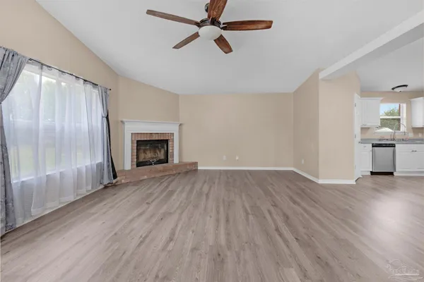 an empty room with wooden floor fireplace and windows