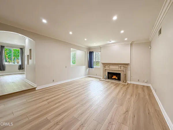 an empty room with wooden floor fireplace and windows