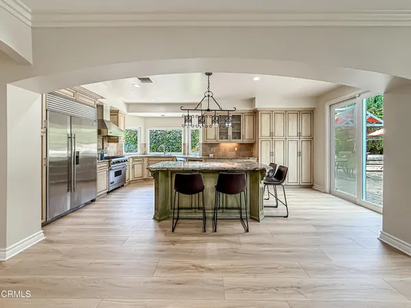 a kitchen with stainless steel appliances a dining table chairs and wooden floor