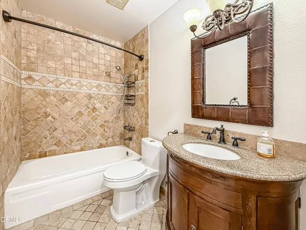 a bathroom with a granite countertop sink mirror vanity and toilet