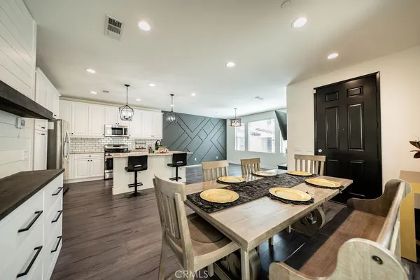 a open dining room with stainless steel appliances kitchen island granite countertop a table chairs and a refrigerator