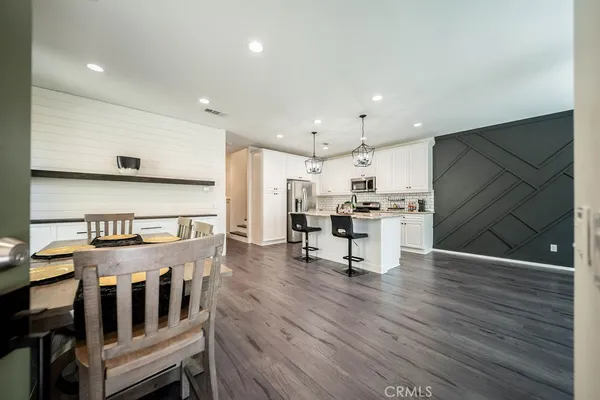 a kitchen with stainless steel appliances kitchen island granite countertop a stove a refrigerator and white cabinets with wooden floors