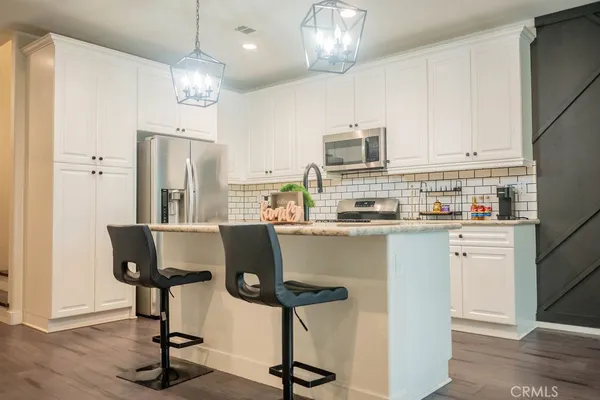 a kitchen with stainless steel appliances kitchen island granite countertop a refrigerator a stove a microwave and cabinets