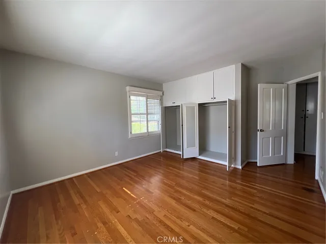 an empty room with wooden floor closet and windows