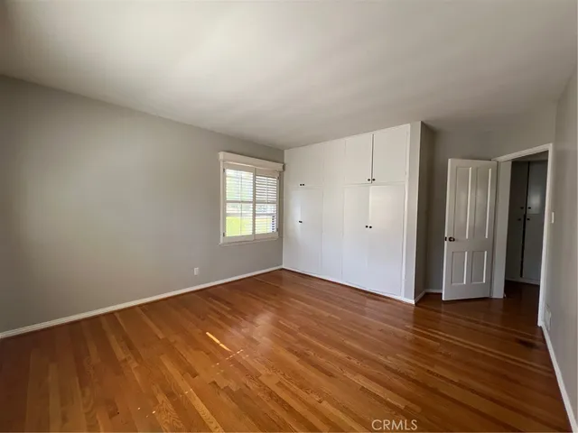 a view of an empty room with wooden floor and window