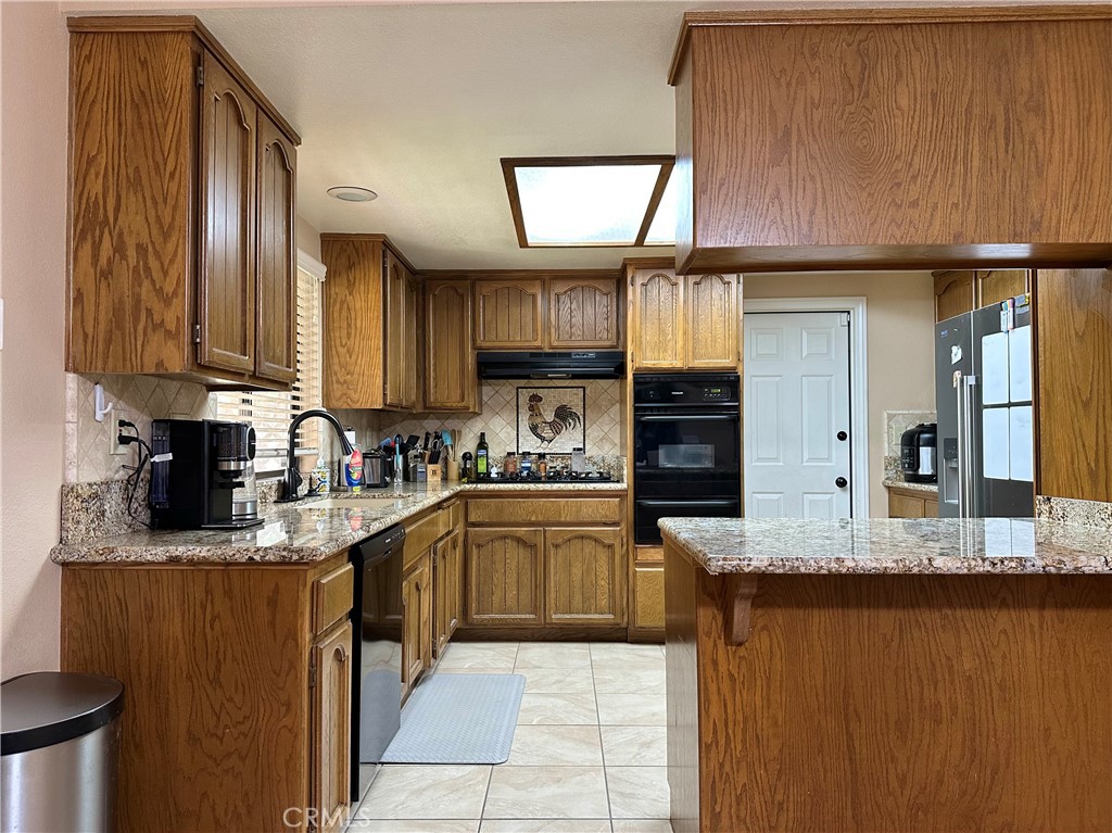 18143 Kalin Ranch Drive Victorville, CA 92395 - Photo 15 of 28 a kitchen with stainless steel appliances granite countertop wooden cabinets a sink and a stove