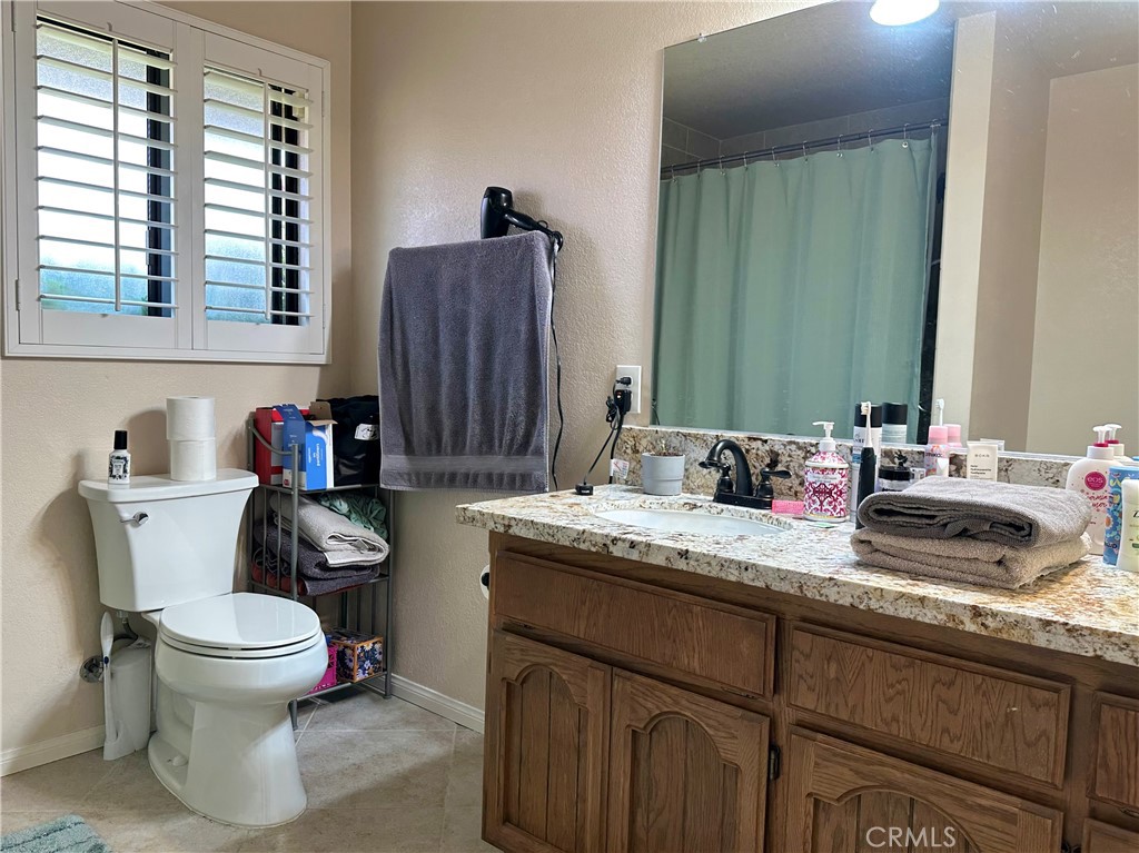 18143 Kalin Ranch Drive Victorville, CA 92395 - Photo 23 of 28 a bathroom with a granite countertop sink toilet and mirror