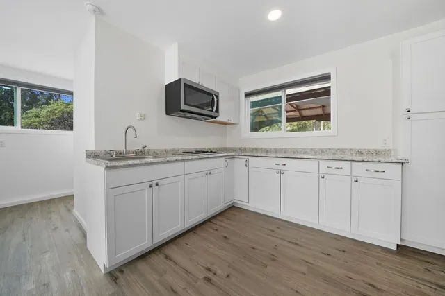 a kitchen with granite countertop white cabinets and a sink