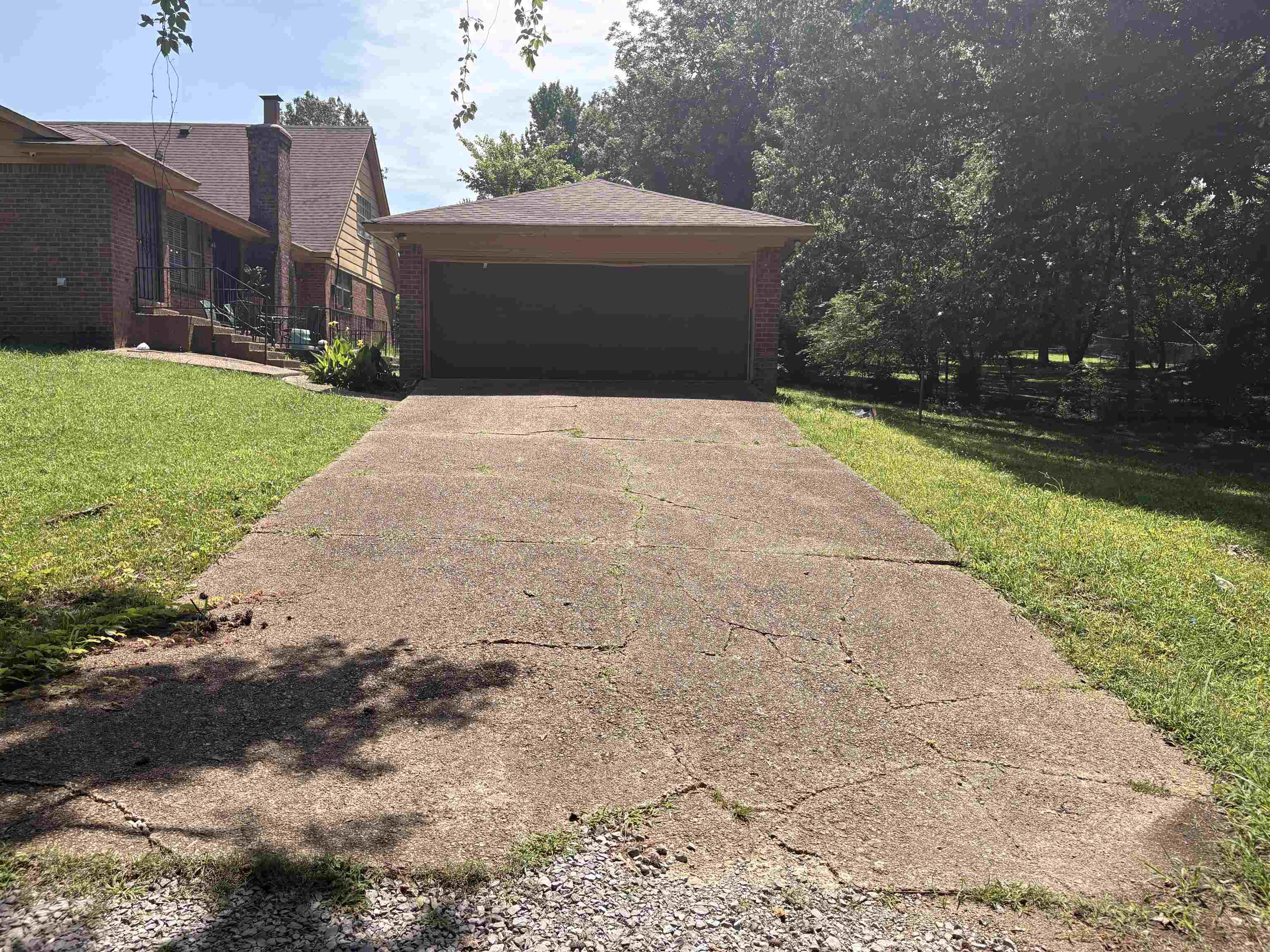 4009 Tessland Road Memphis, TN 38128 - Photo 14 of 16 Attached garage with a dark panel door, set back from a concrete driveway