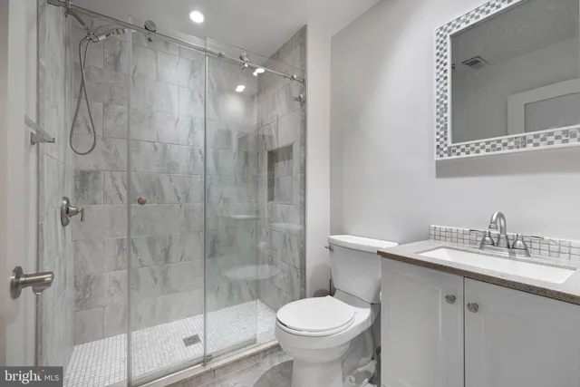 a bathroom with a shower sink vanity and toilet