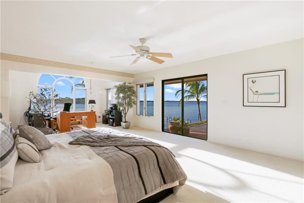 171 South River Road Stuart, FL 34996 - Photo 52 of 68 a bedroom with a large bed and a chandelier