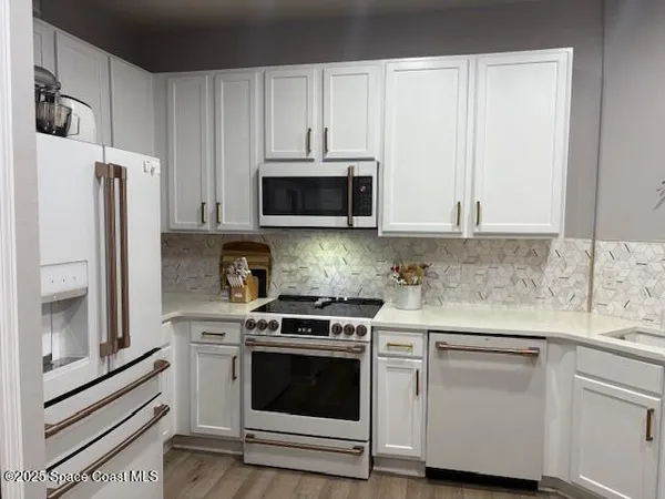 a kitchen with white cabinets and stainless steel appliances