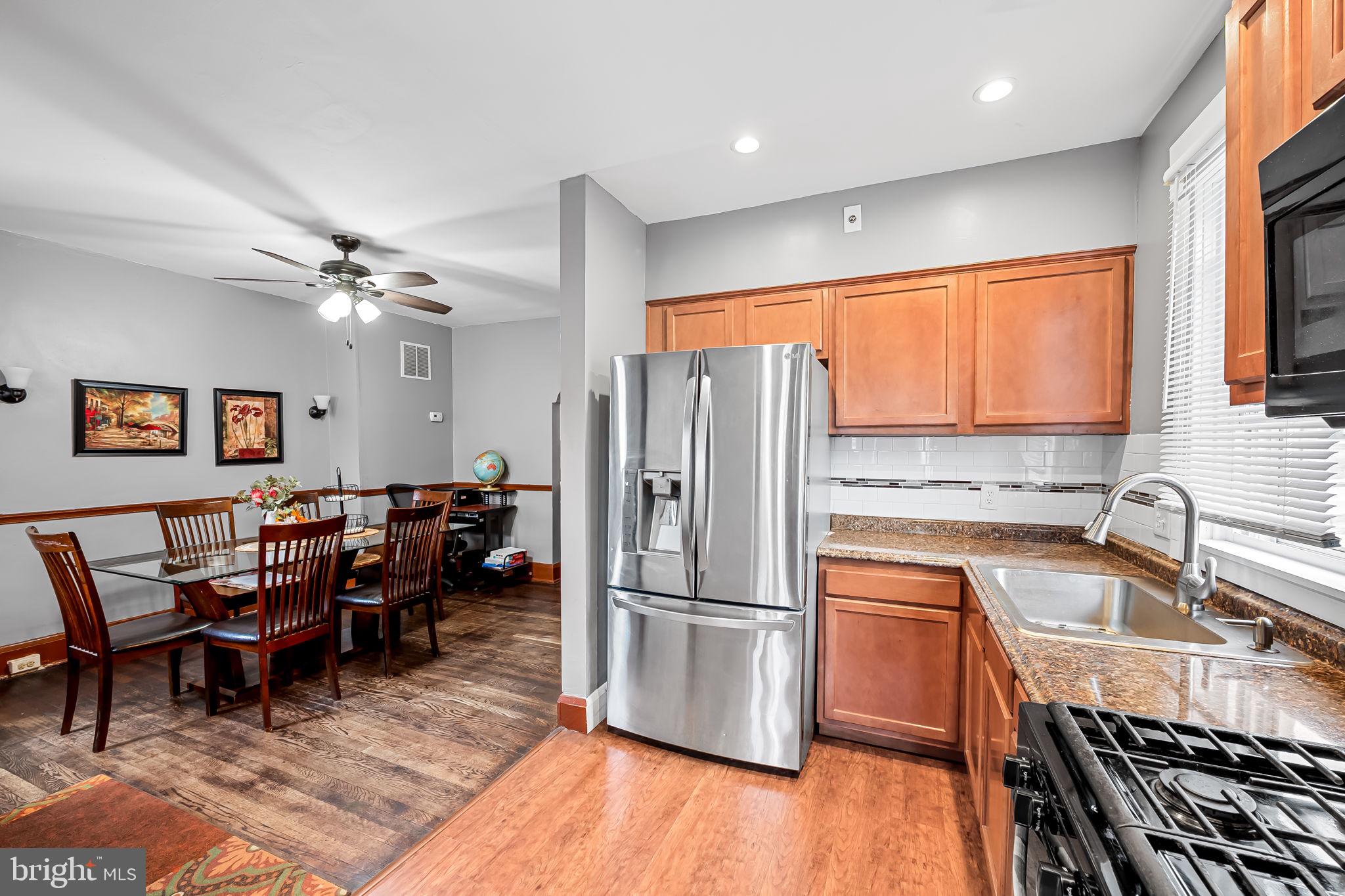 2908 East Cold Spring Lane Baltimore, MD 21214 - Photo 6 of 19 a kitchen with stainless steel appliances granite countertop a refrigerator a sink dishwasher a dining table and chairs with wooden floor