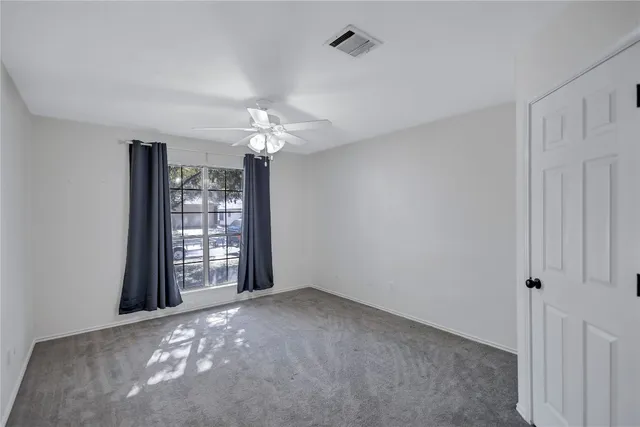 an empty room with windows and chandelier fan
