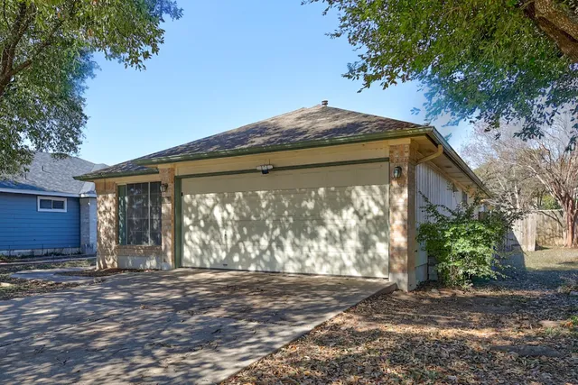 a backyard of a house with large trees and a wooden bench