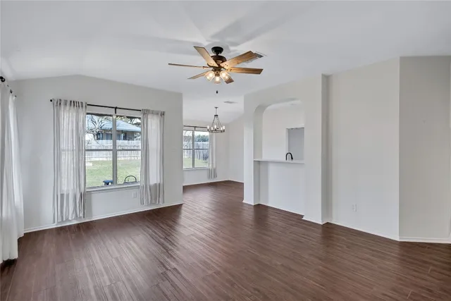 a view of an empty room with window and wooden floor
