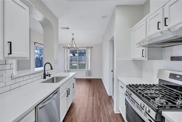 a kitchen with granite countertop a sink stove and cabinets