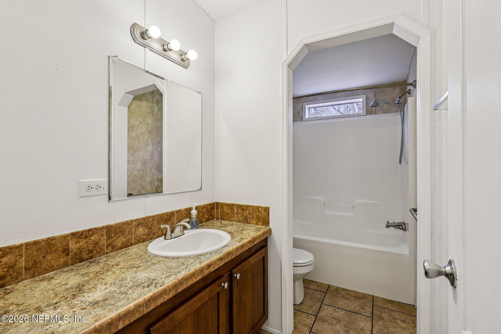 13725 Webb Road Jacksonville, FL 32218 - Photo 34 of 61 a bathroom with a granite countertop sink a mirror and a bathtub