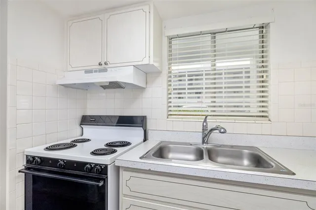 a kitchen with granite countertop a sink stove top oven and cabinets