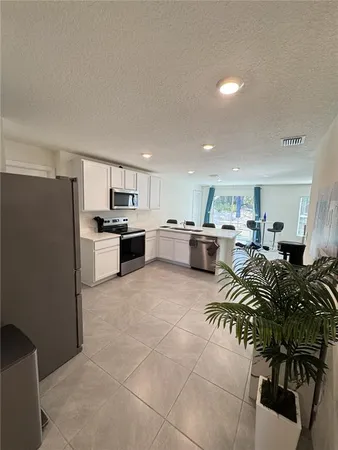 a kitchen with stainless steel appliances a table and chairs in it