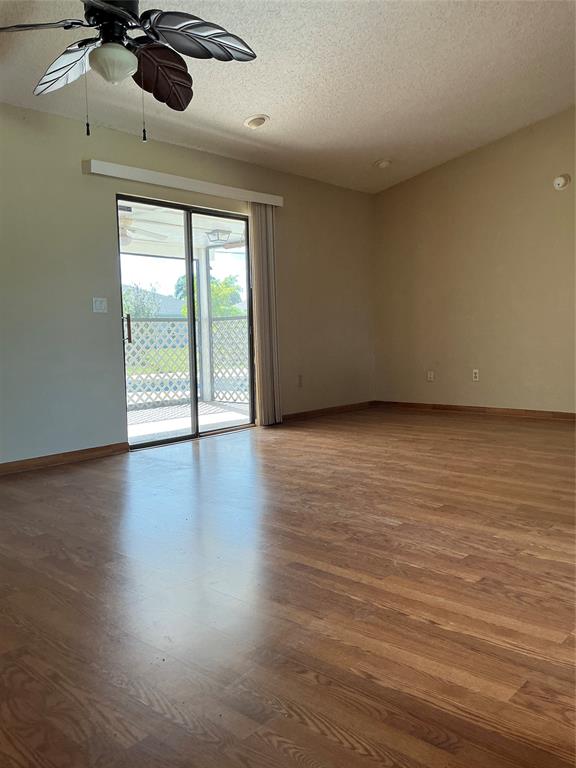 1858 Southwest Capehart Avenue Port St. Lucie, FL 34953 - Photo 3 of 11 an empty room with wooden floor fan and windows