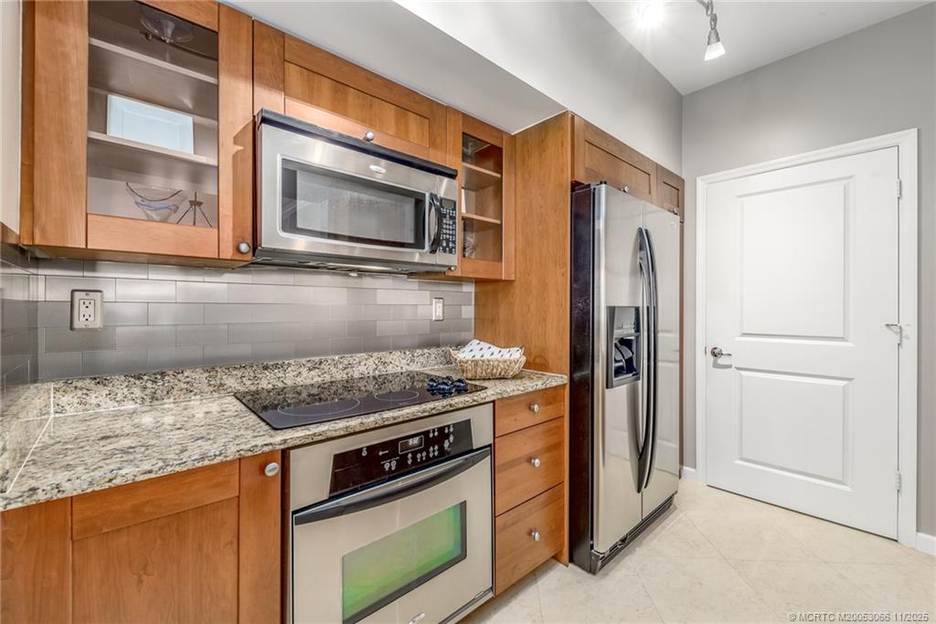 715 Northwest Flagler Avenue, Unit 202 Stuart, FL 34994 - Photo 5 of 26 a kitchen with stainless steel appliances granite countertop a stove microwave and refrigerator