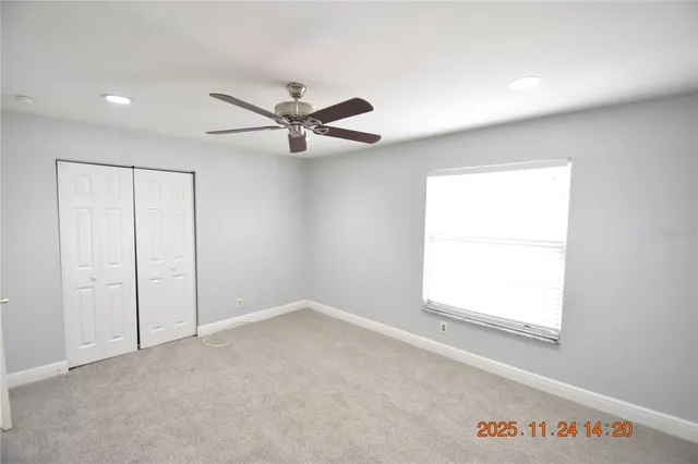 an empty room with a window and a ceiling fan