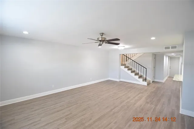 a view of an empty room with wooden floor and a chandelier