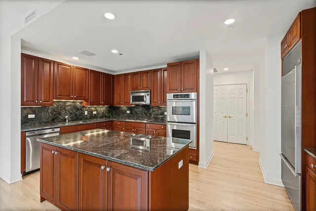 a kitchen with stainless steel appliances granite countertop a stove a sink and a refrigerator