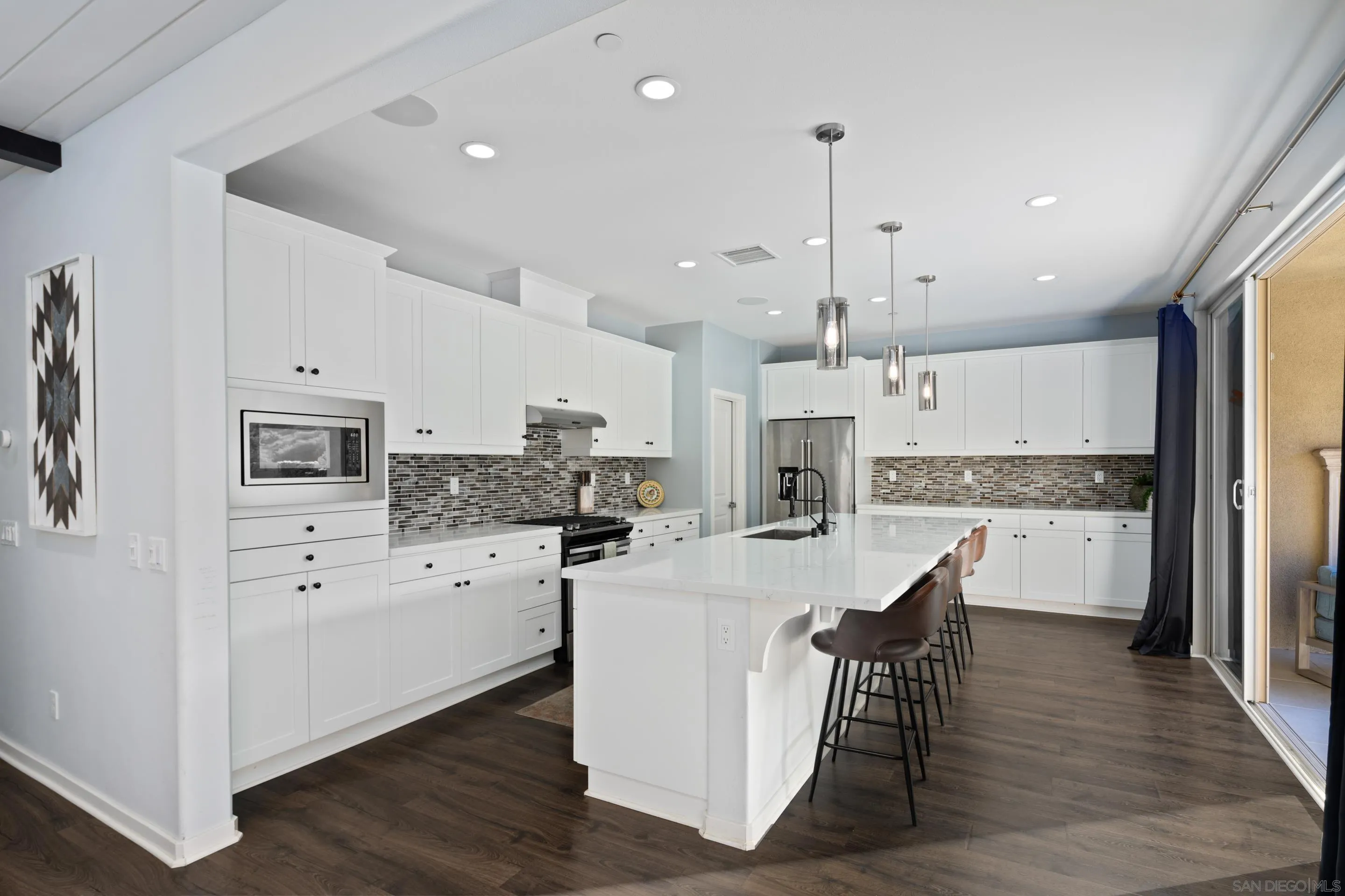 8932 Hightail Drive Santee, CA 92071 - Photo 5 of 20 a kitchen with stainless steel appliances kitchen island granite countertop a stove a refrigerator a oven a sink a dining table and chairs with wooden floor