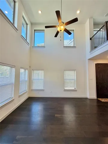 a view of an empty room with wooden floor and a ceiling fan
