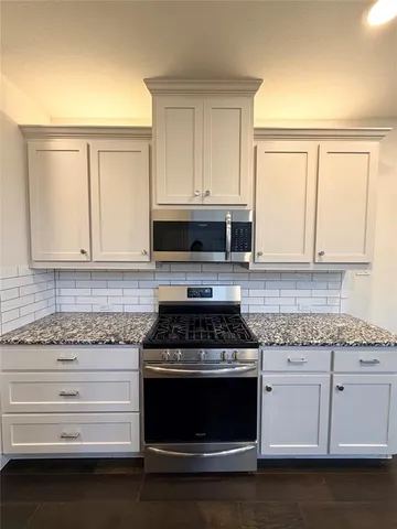 a kitchen with granite countertop white cabinets and appliances