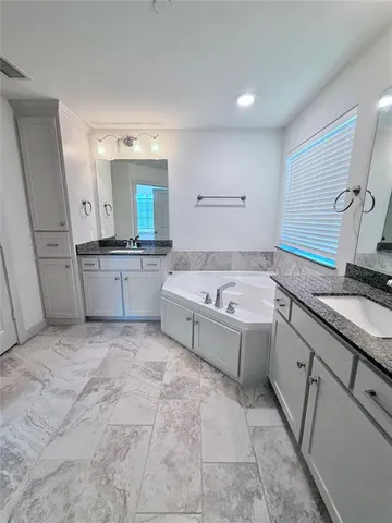 a large white bathroom with a sink a bathtub and a double vanity sink