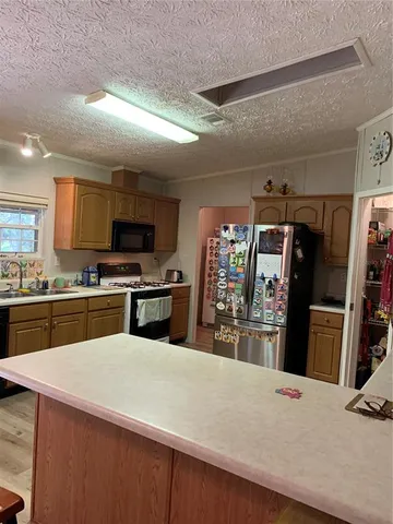 a kitchen with stainless steel appliances wooden floor and living room view
