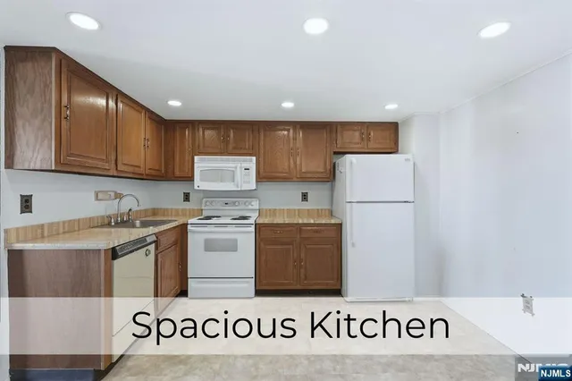 a kitchen with a refrigerator a stove top oven and a sink with wooden floor