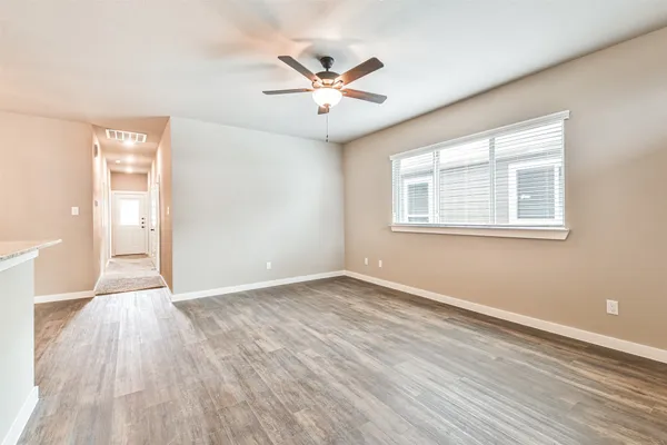 a view of an empty room with wooden floor and a window