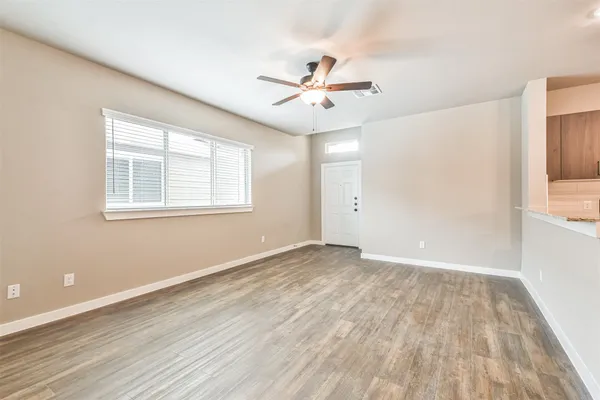 an empty room with wooden floor fan and windows