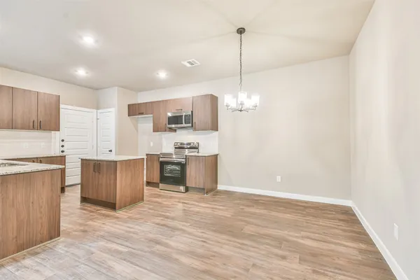 a open kitchen with stainless steel appliances granite countertop a refrigerator a stove top oven a sink dishwasher and a wooden cabinets