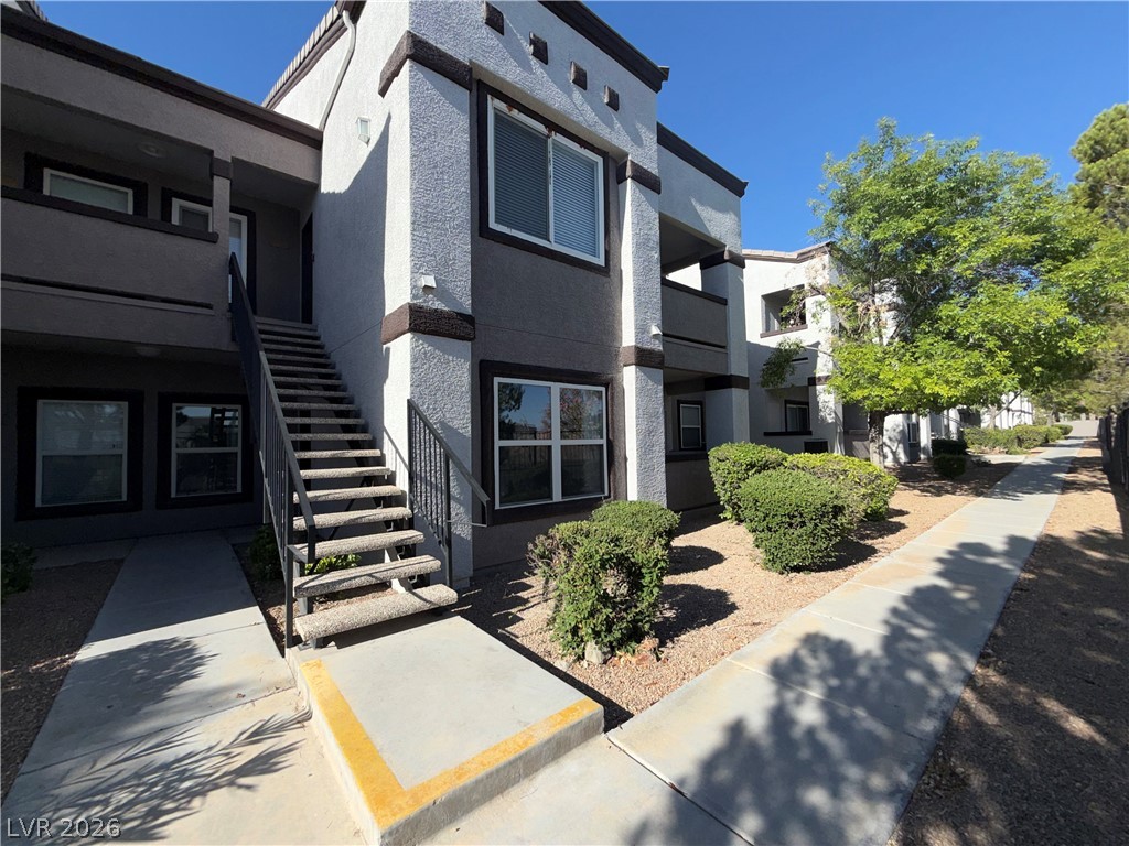 A welcoming entry staircase leads to residences within a thoughtfully landscaped multi-story complex.
